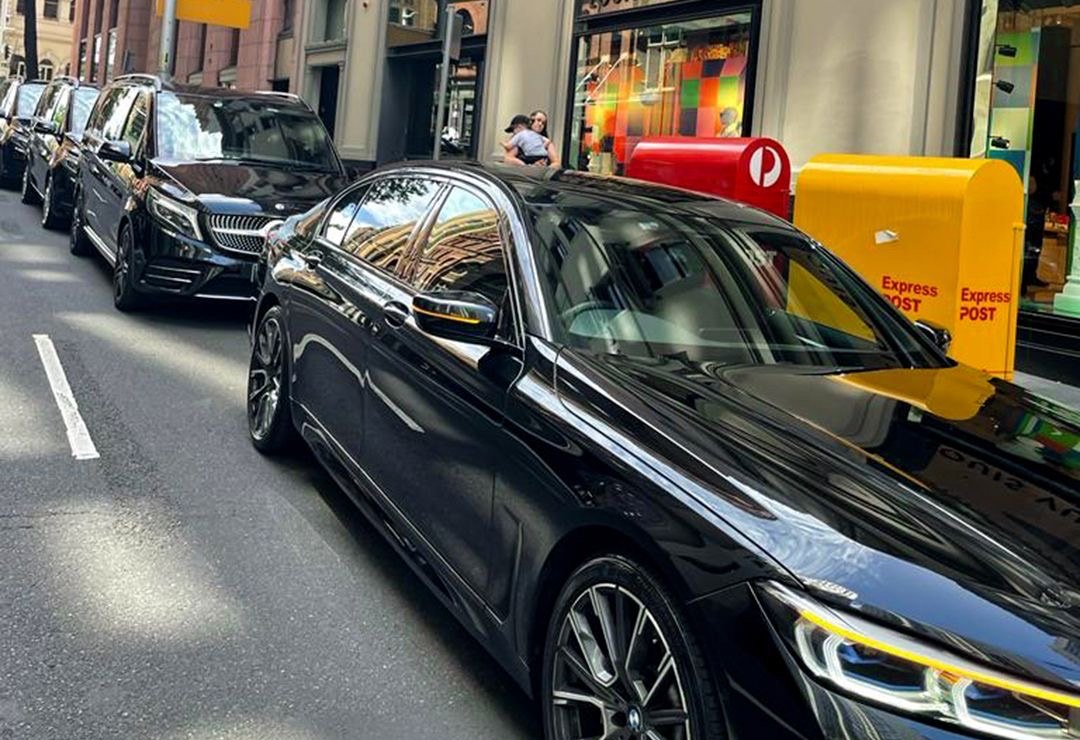A line of protection vehicles held on a city street, the lead car waiting at the kerb.