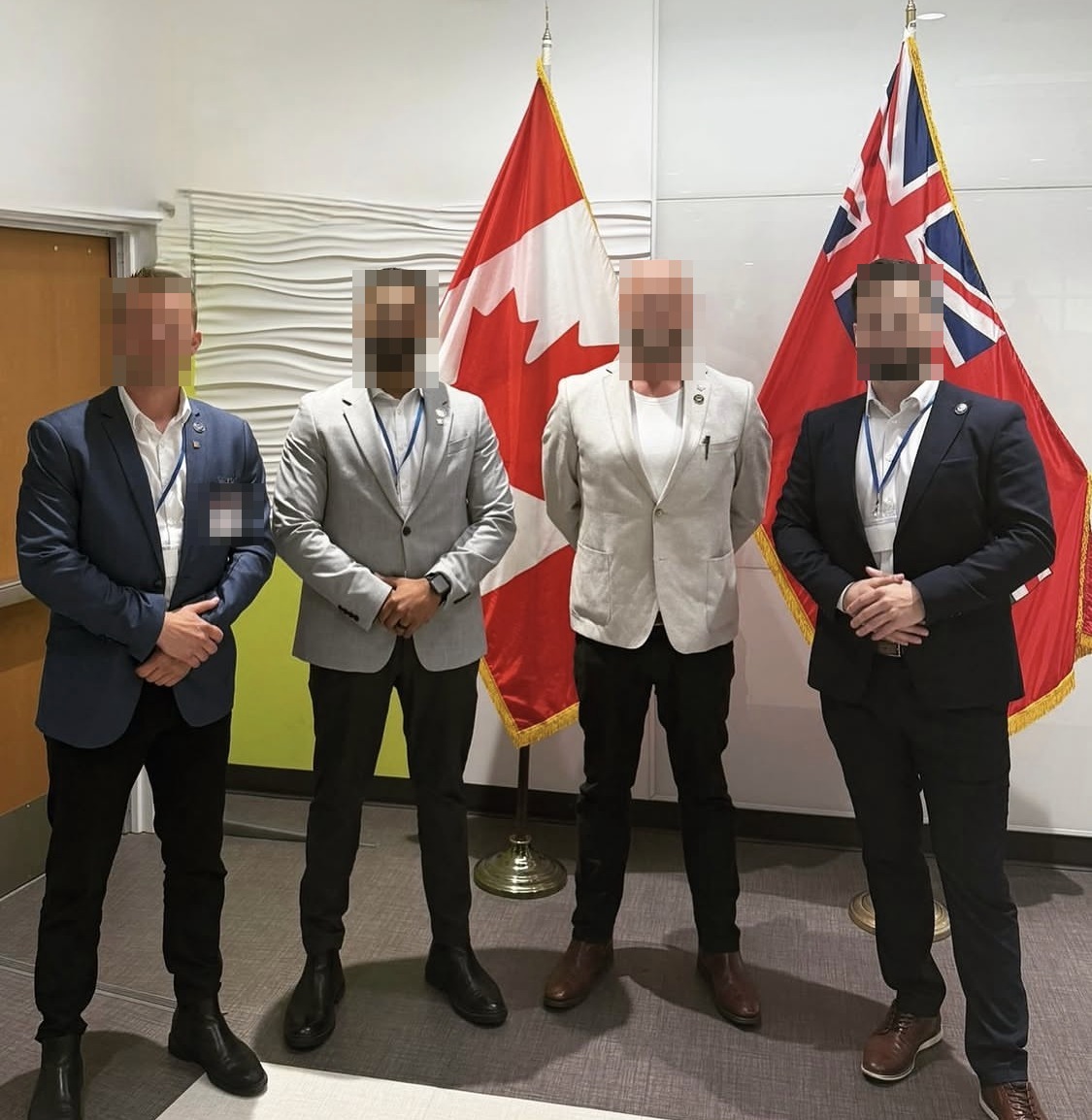 Four members of the team at a defence industry conference, national flags behind them.